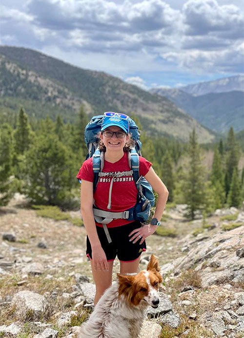 a woman hiking with her dog in the mountains.