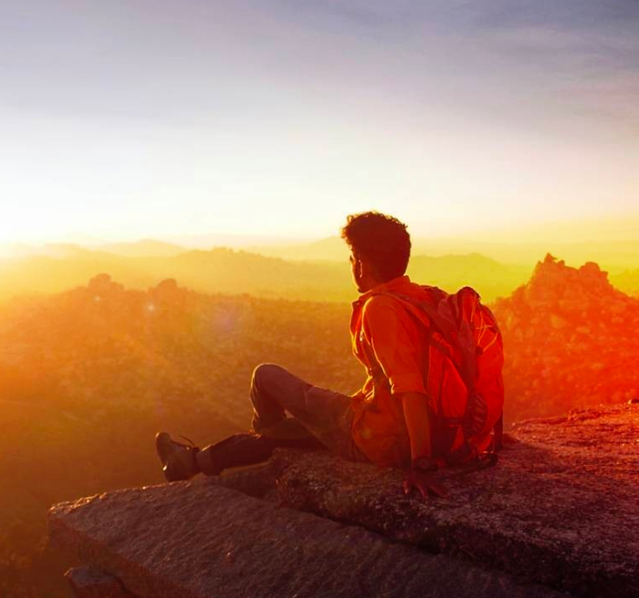 a man sitting on top of a mountain with a backpack.