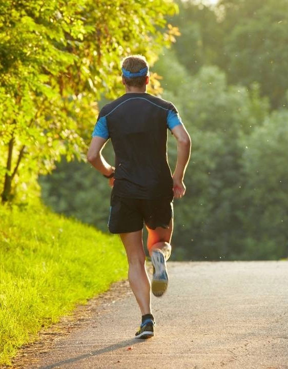 a man running down a road with trees in the background.