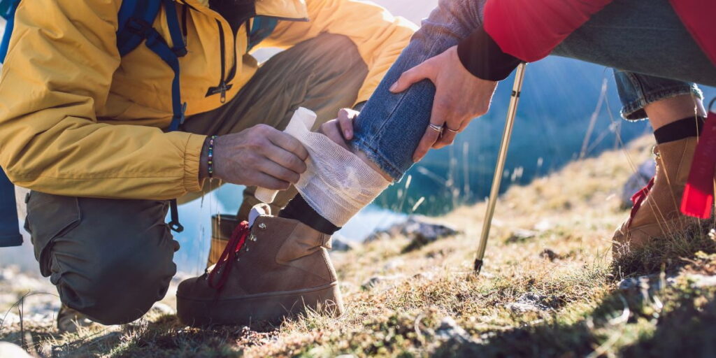 a man is putting a bandage on a hiker's leg.